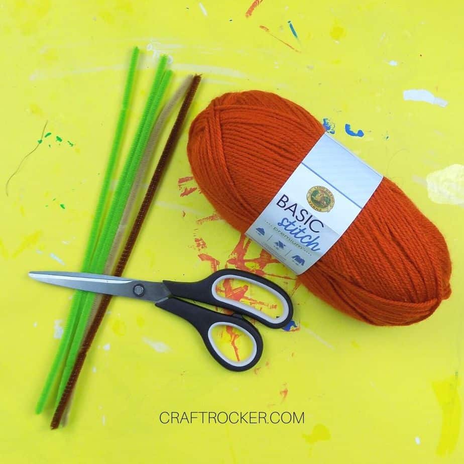 Orange Spool of Yarn next to Scissors and Pipe Cleaners - Craft Rocker