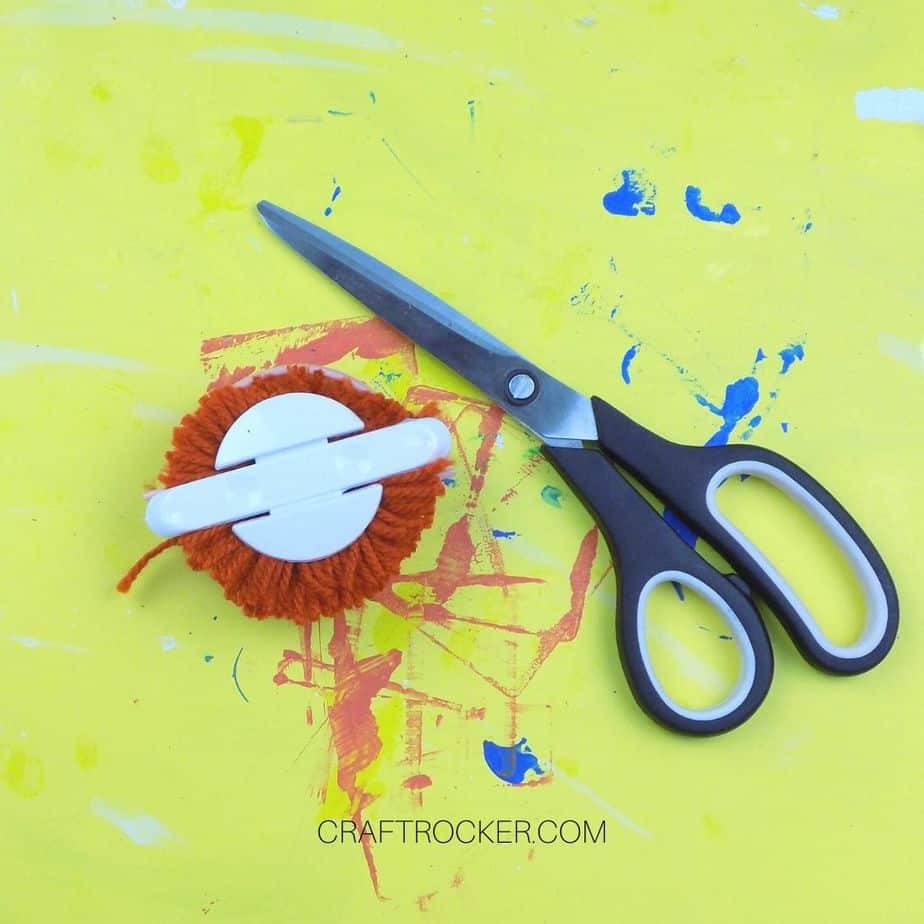 Scissors next to Cut Yarn on Pom Pom Maker - Craft Rocker