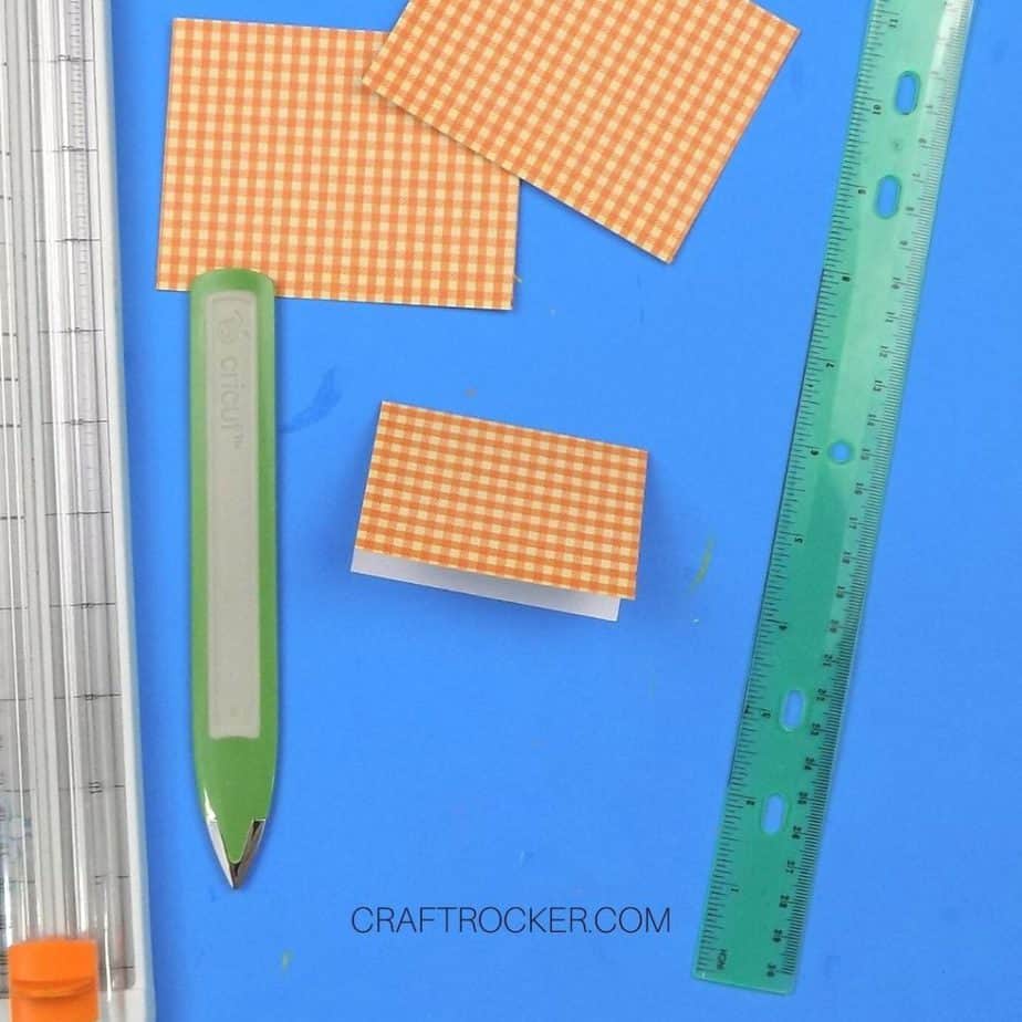 Close Up of Folded Piece of Orange Plaid Paper next to Boning Tool and Ruler - Craft Rocker