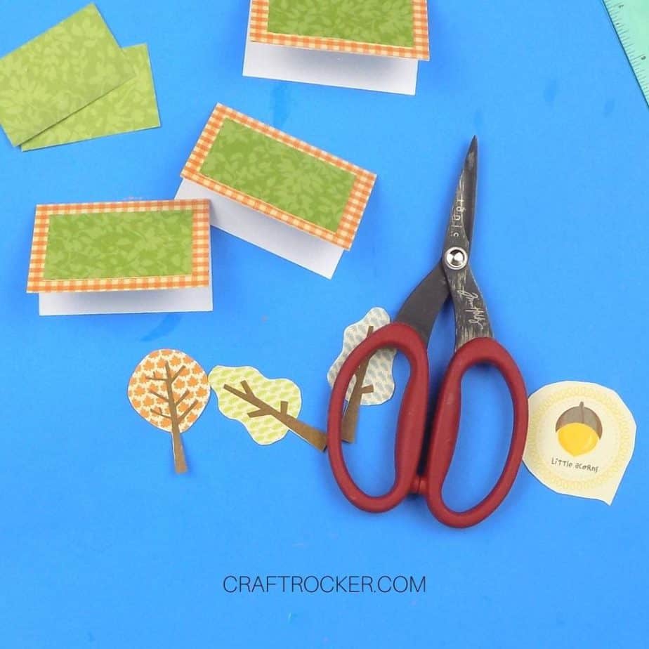 Cut Out Paper Trees next to Scissors and Place Cards - Craft Rocker