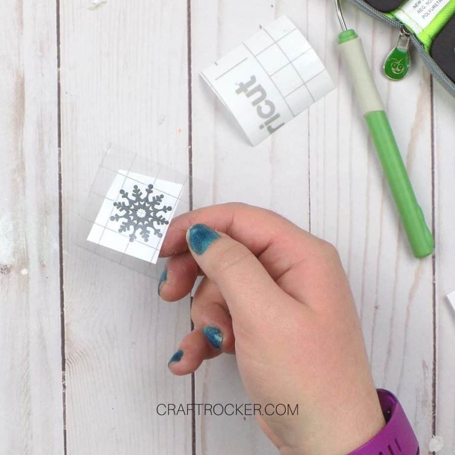 Hand Holding Transfer Tape On Silver Snowflake - Craft Rocker