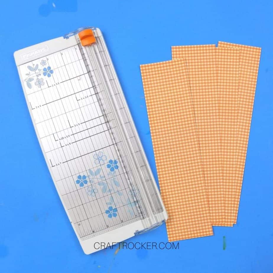 Strips of Orange Plaid Paper next to Paper Cutter - Craft Rocker