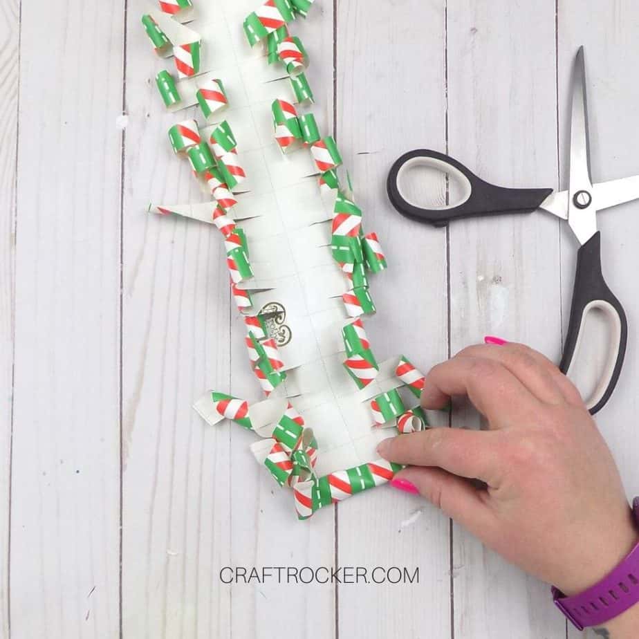 Hand Rolling End of Curled Wrapping Paper next to Scissors - Craft Rocker