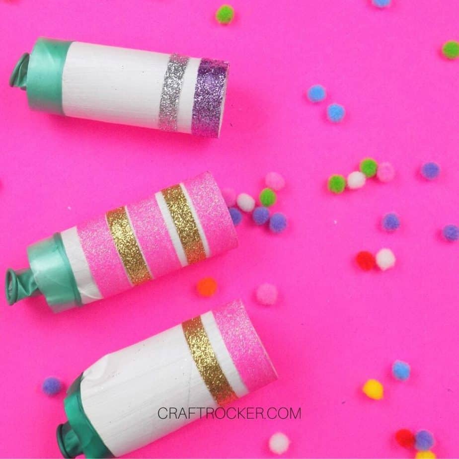 Glitter New Years Poppers on Pink Background next to Pompoms - Craft Rocker