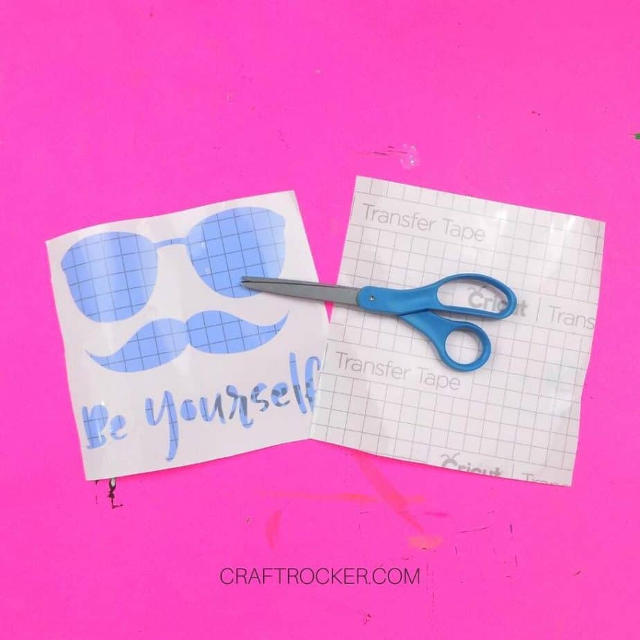 Scissors on top of Be Yourself Vinyl Stencil and Transfer Tape - Craft Rocker