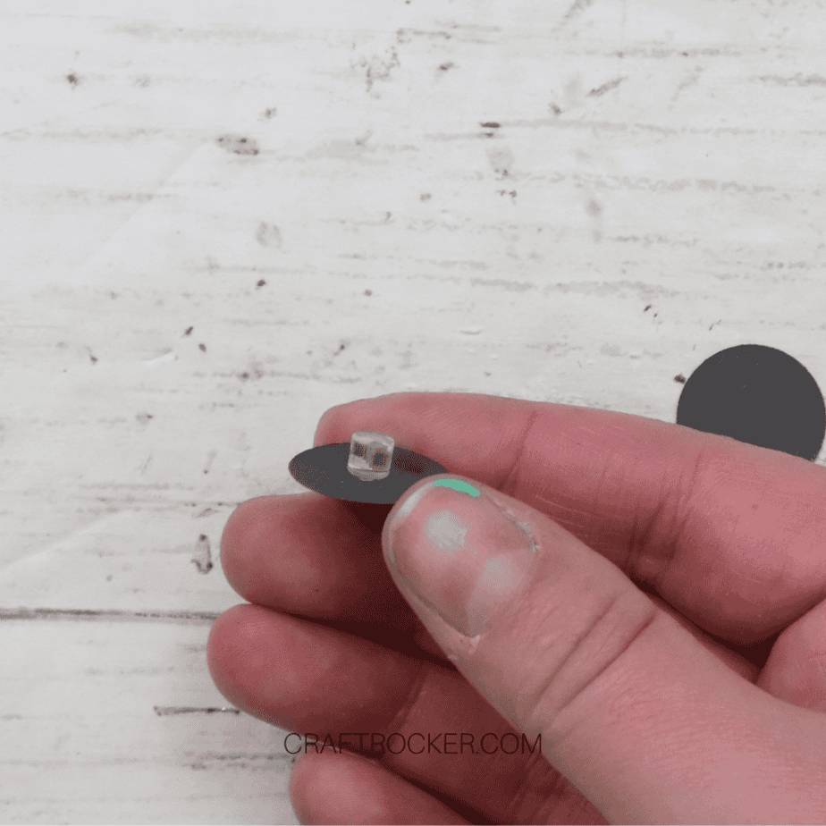 Close Up of Hand Holding Black Paper Circle with Plastic Cylinder Attached to It - Craft Rocker