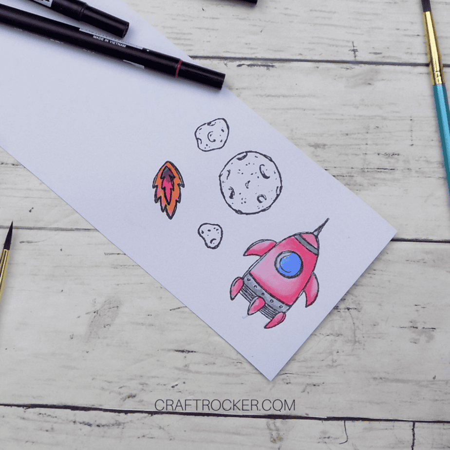 Colored Spaceship and Fire on Watercolor Paper next to Stamped Meteors - Craft Rocker